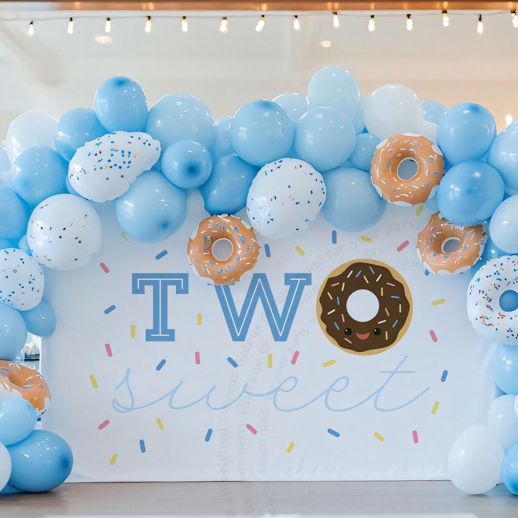 Chocolate donut two sweet backdrop under a blue and white balloon arch with donut balloons.