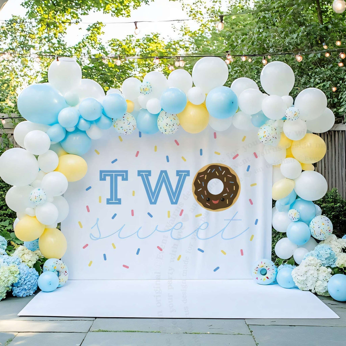 Chocolate donut two sweet backdrop in a garden with blue balloons and hydrangeas.