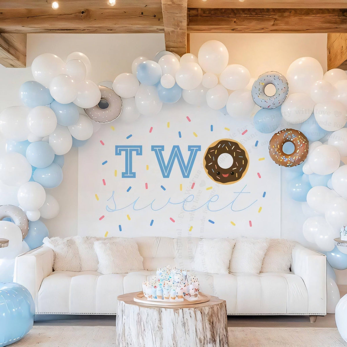 Chocolate donut backdrop behind a white sofa and a sprinkle cake on a wood table.