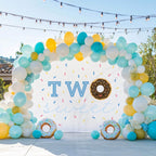 Two sweet donut backdrop on a patio with teal, yellow and white balloons.