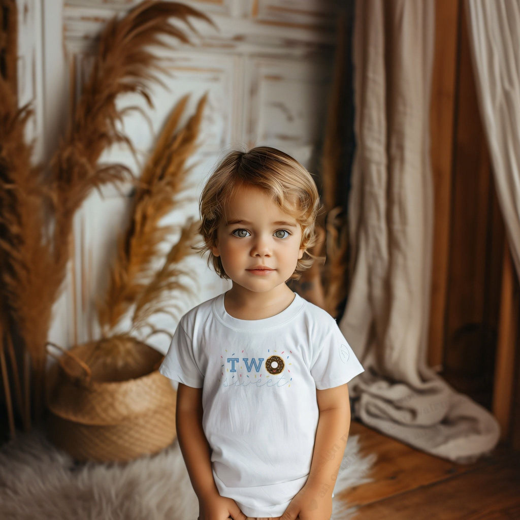 Toddler boy in a white Two Sweet tee with a chocolate donut for the O.