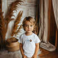 Toddler boy in a white Two Sweet tee with a chocolate donut for the O.