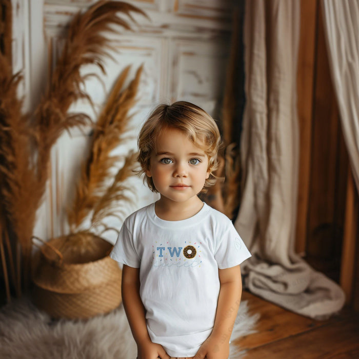 Toddler boy in a white Two Sweet tee with a chocolate donut for the O.