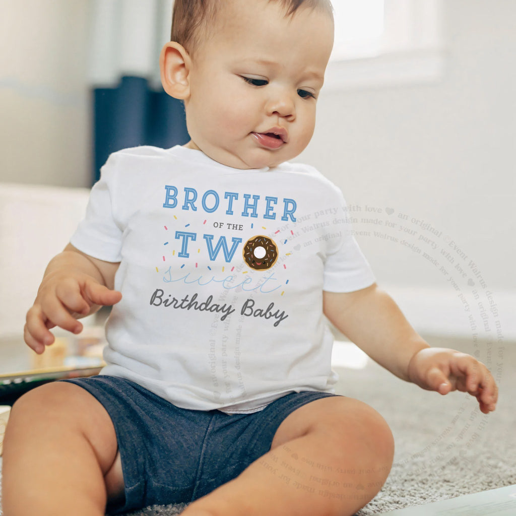 Baby boy sitting on a rug in a white Brother of the Two Sweet baby tee.