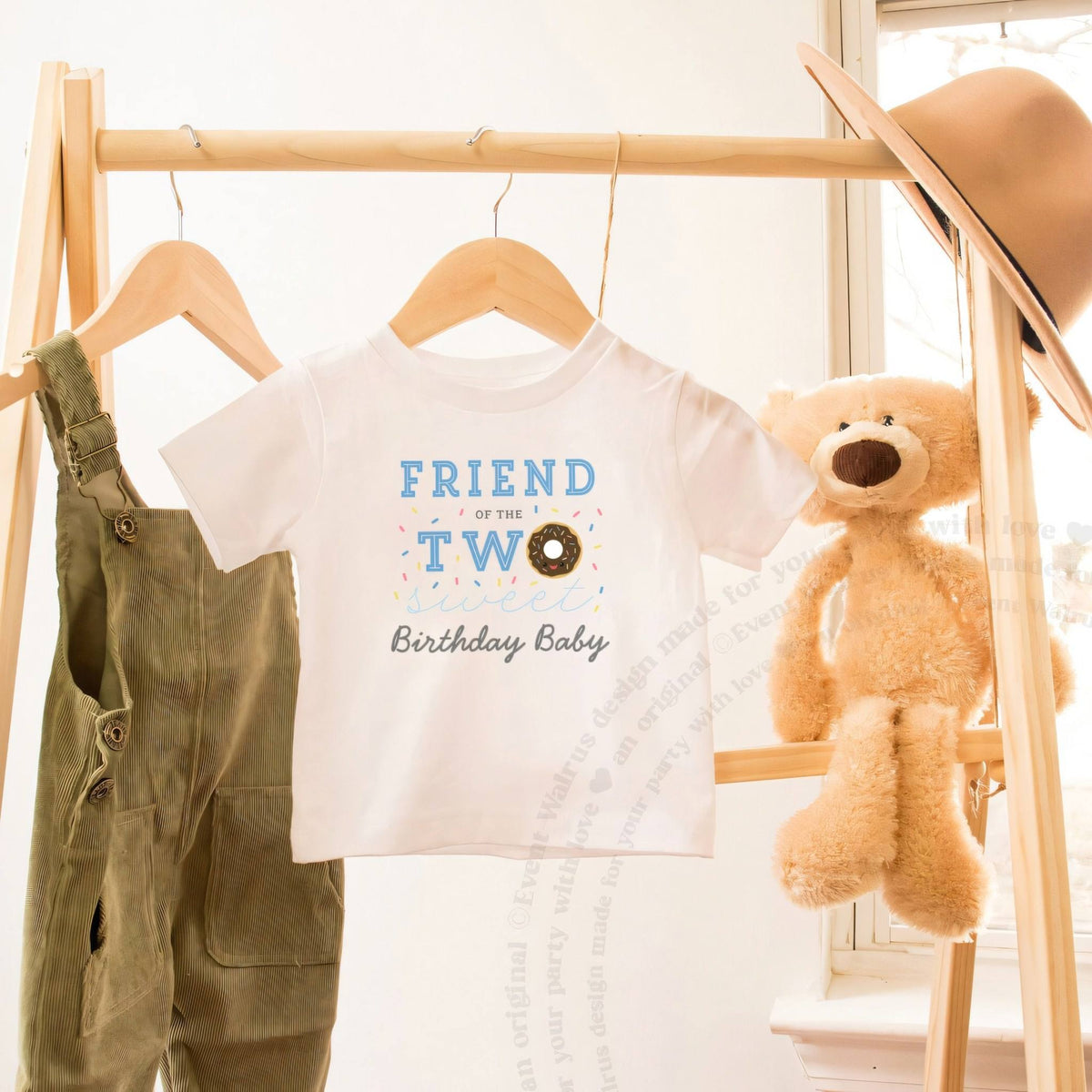White Friend of the Two Sweet toddler tee on a wooden clothes rack beside a teddy bear.
