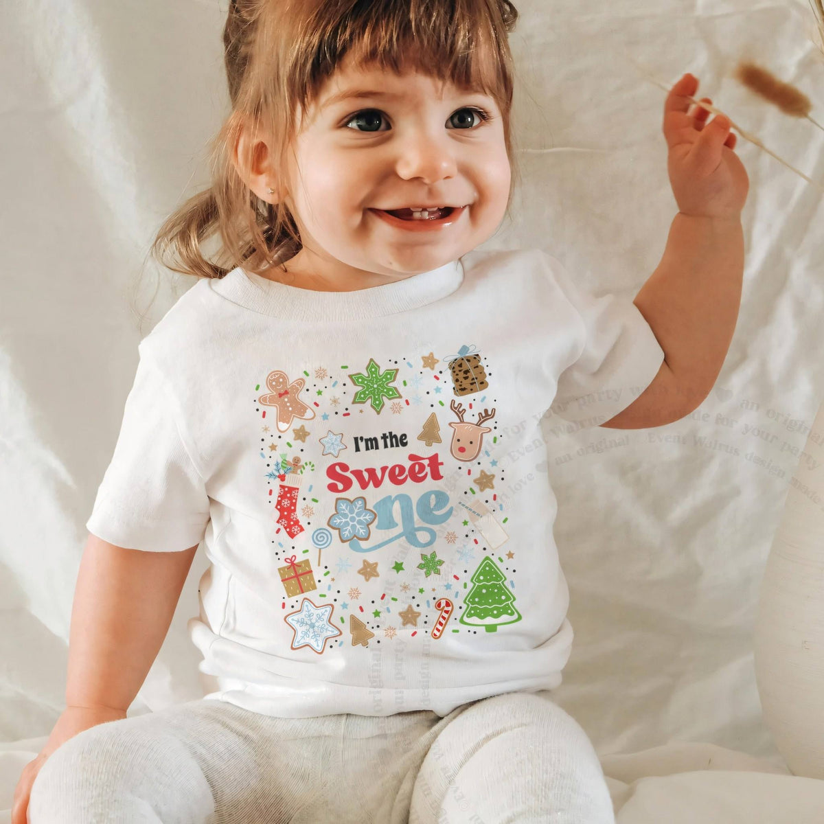 Laughing baby girl in a white I'm the Sweet One baby tee.