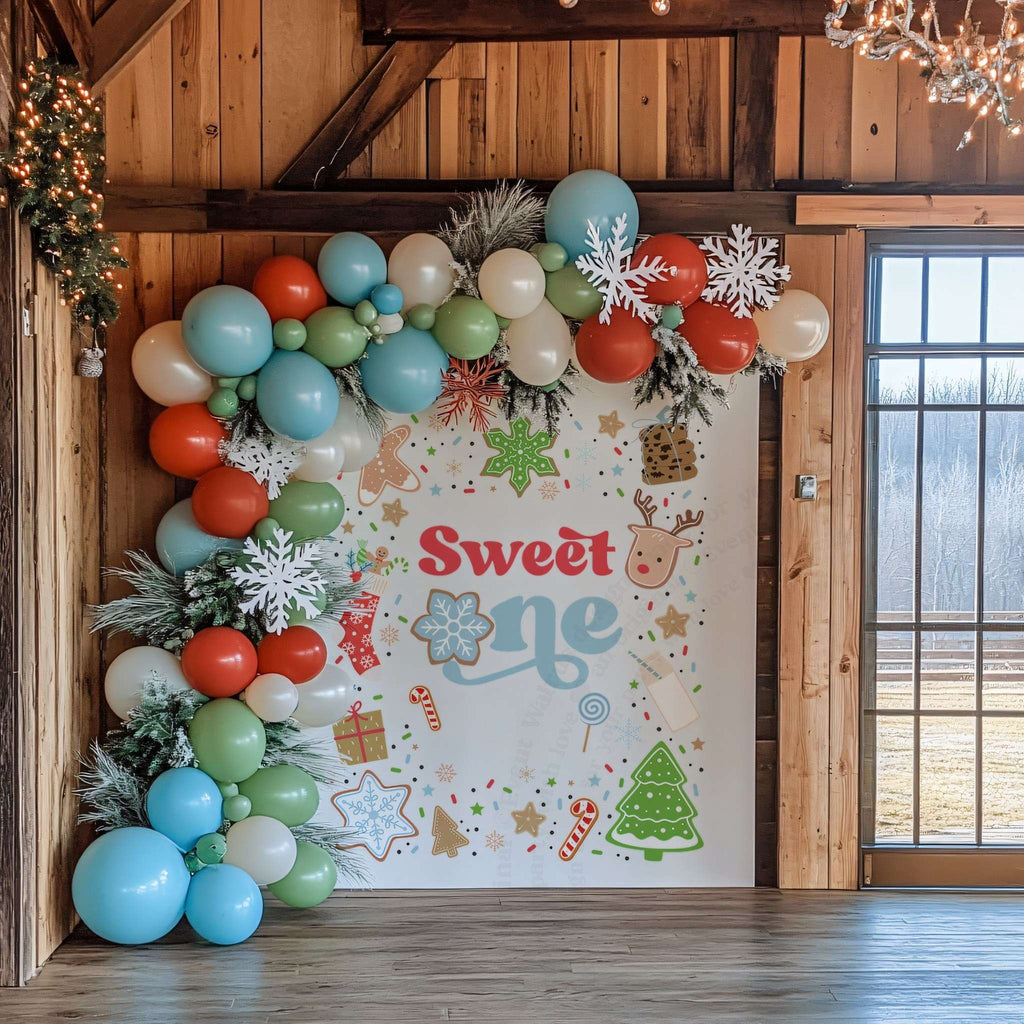 Christmas cookie backdrop in a barn room framed by red, green and blue balloons.