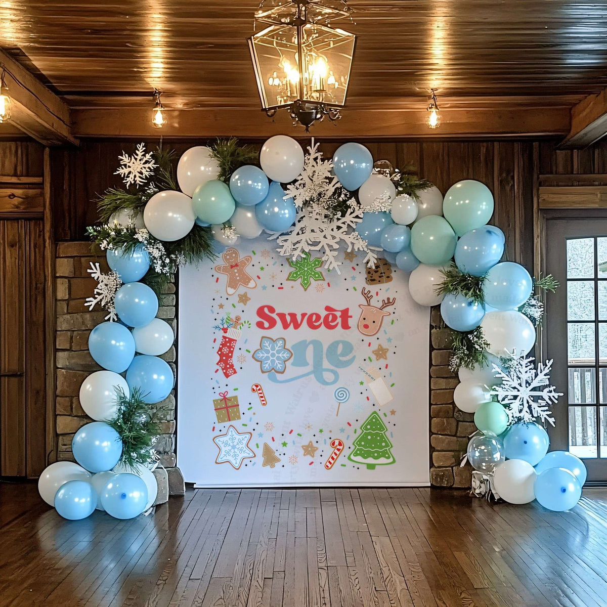 Sweet one Christmas cookie backdrop in a wood hall under a blue and white balloon arch.