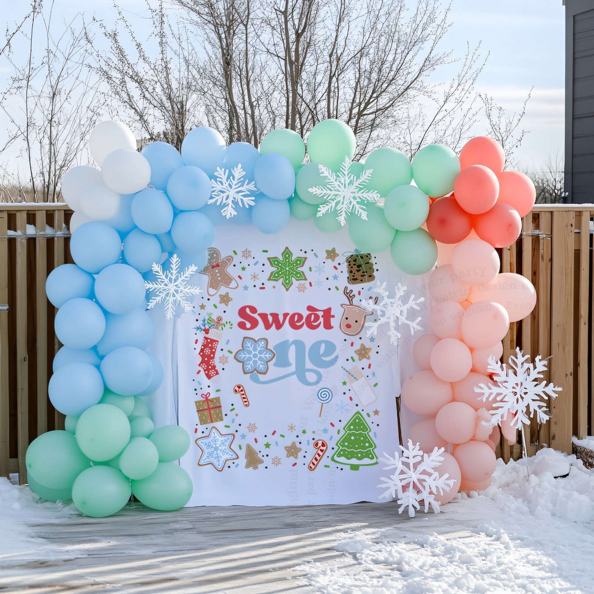 Christmas cookie sweet one backdrop on a snowy deck with blue, mint and coral balloons and snowflakes.