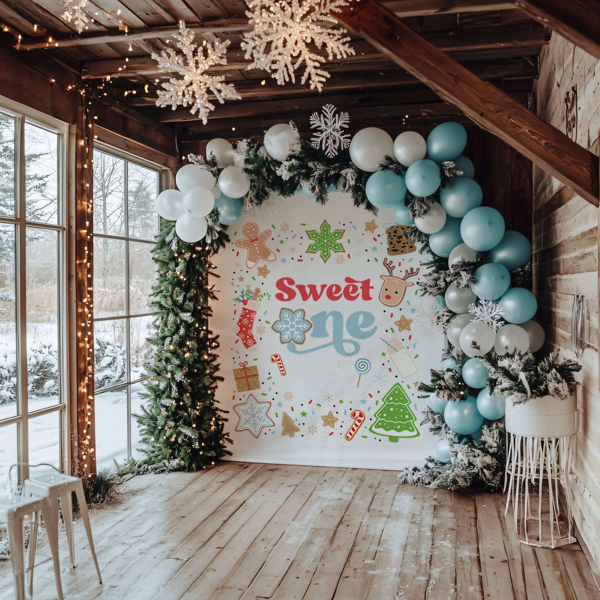 Christmas cookie sweet one backdrop in a sunroom with blue balloons and a lit garland.