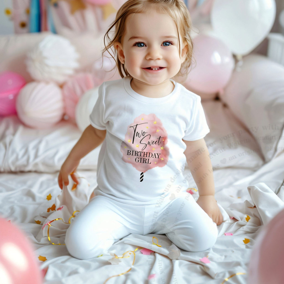 Smiling toddler girl among pink balloons in a white Two Sweet Birthday Girl cotton candy tee.