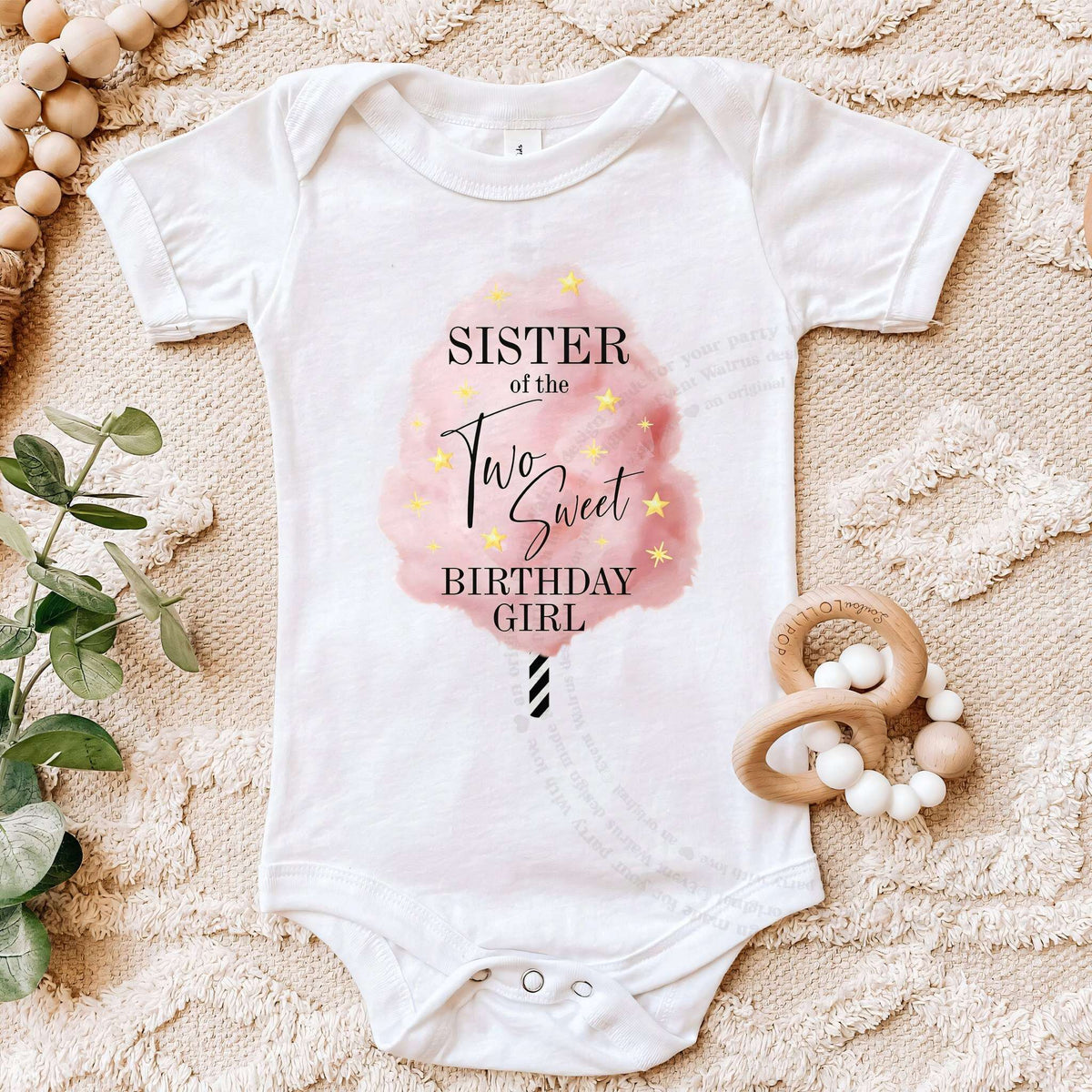 White Sister of the Two Sweet bodysuit on a beige blanket with a wooden teether.