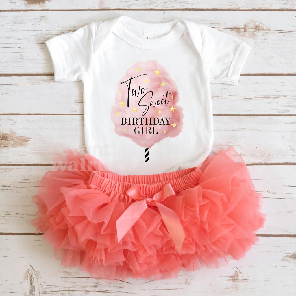 White cotton candy Two Sweet bodysuit laid flat with a coral tutu on whitewashed wood.