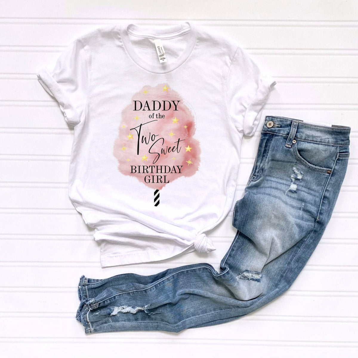 White Daddy of the Two Sweet tee laid flat beside jeans.