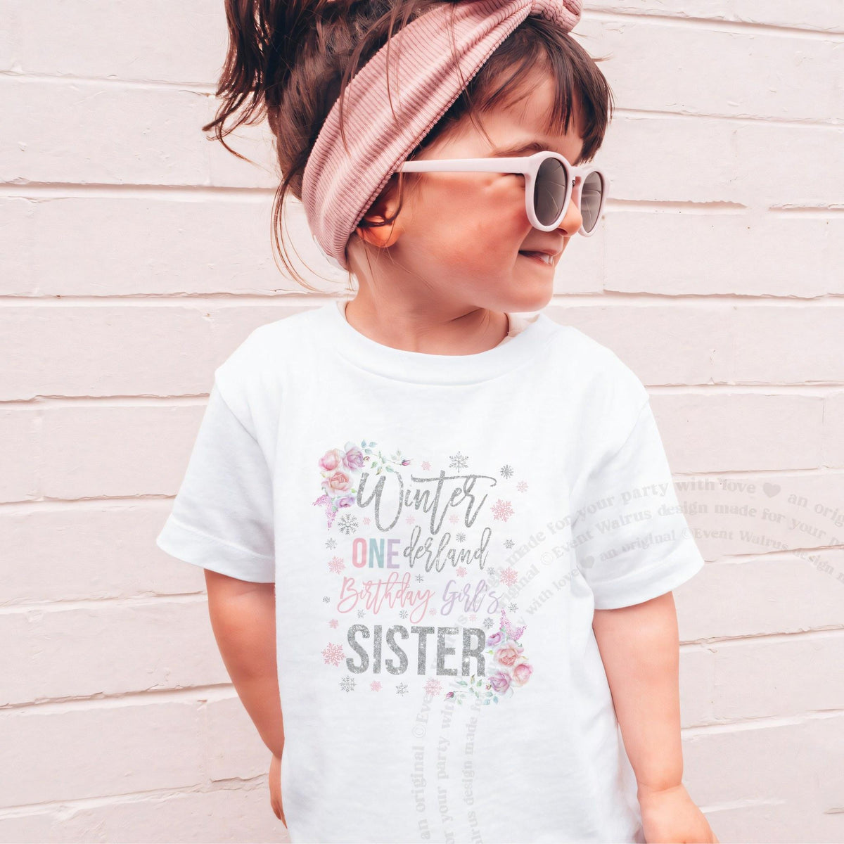 Girl in sunglasses and a pink headband wearing a white floral Winter ONEderland Sister shirt.
