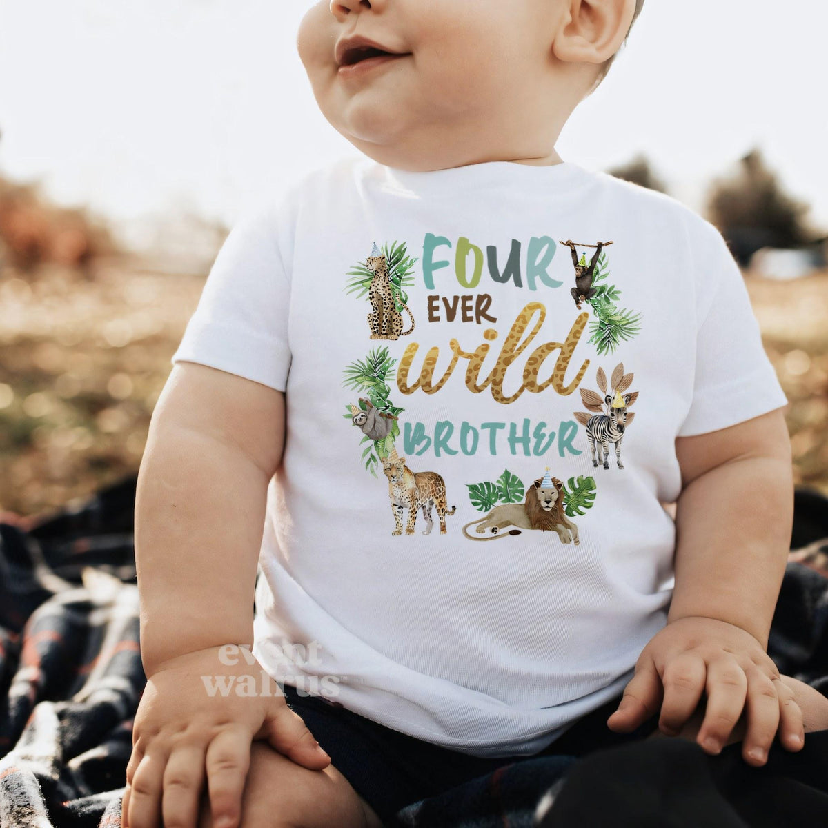 Baby boy sitting outdoors in a white Four Ever Wild Brother baby tee.