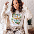 Woman in a cream cardigan wearing a white Four Ever Wild Mom shirt with safari animals.
