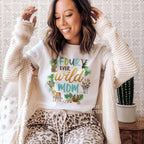 Woman in a cream cardigan wearing a white Four Ever Wild Mom shirt with safari animals.