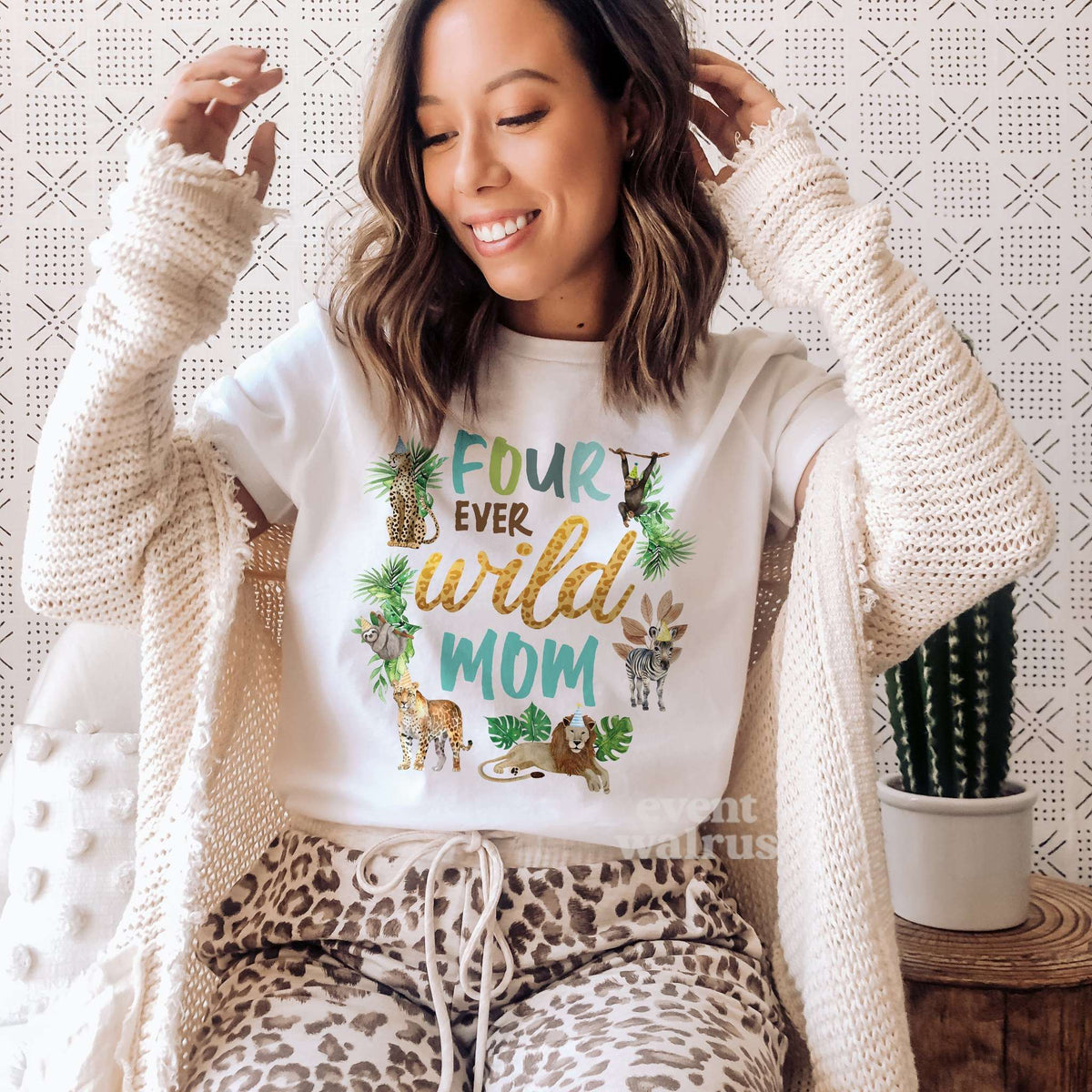 Woman in a cream cardigan wearing a white Four Ever Wild Mom shirt with safari animals.