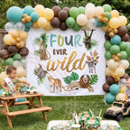 Four ever wild backdrop in a backyard with kids at a picnic table and a safari balloon arch.