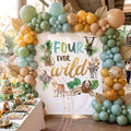 Four ever wild backdrop under a sage, gold and teal balloon arch at a zoo-themed party.