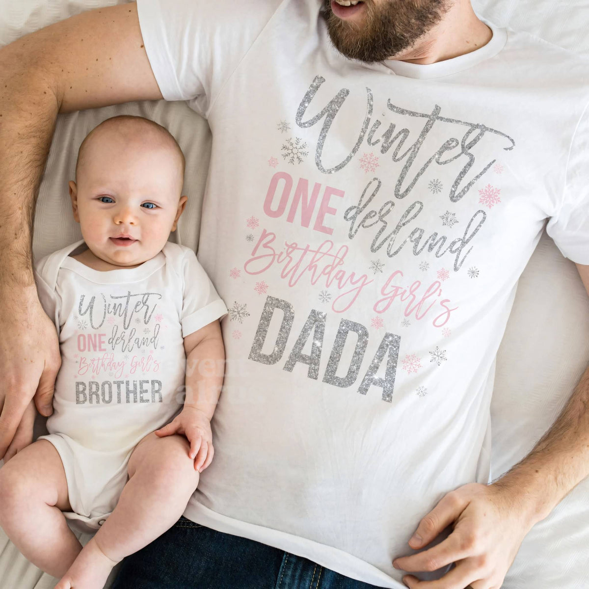Baby in a white Winter ONEderland Brother bodysuit lying on Dad in his Dada shirt.
