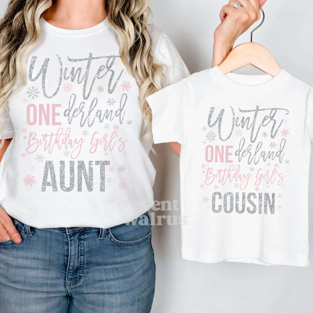 Aunt holding up a white Winter ONEderland Cousin tee on a hanger while wearing her own.