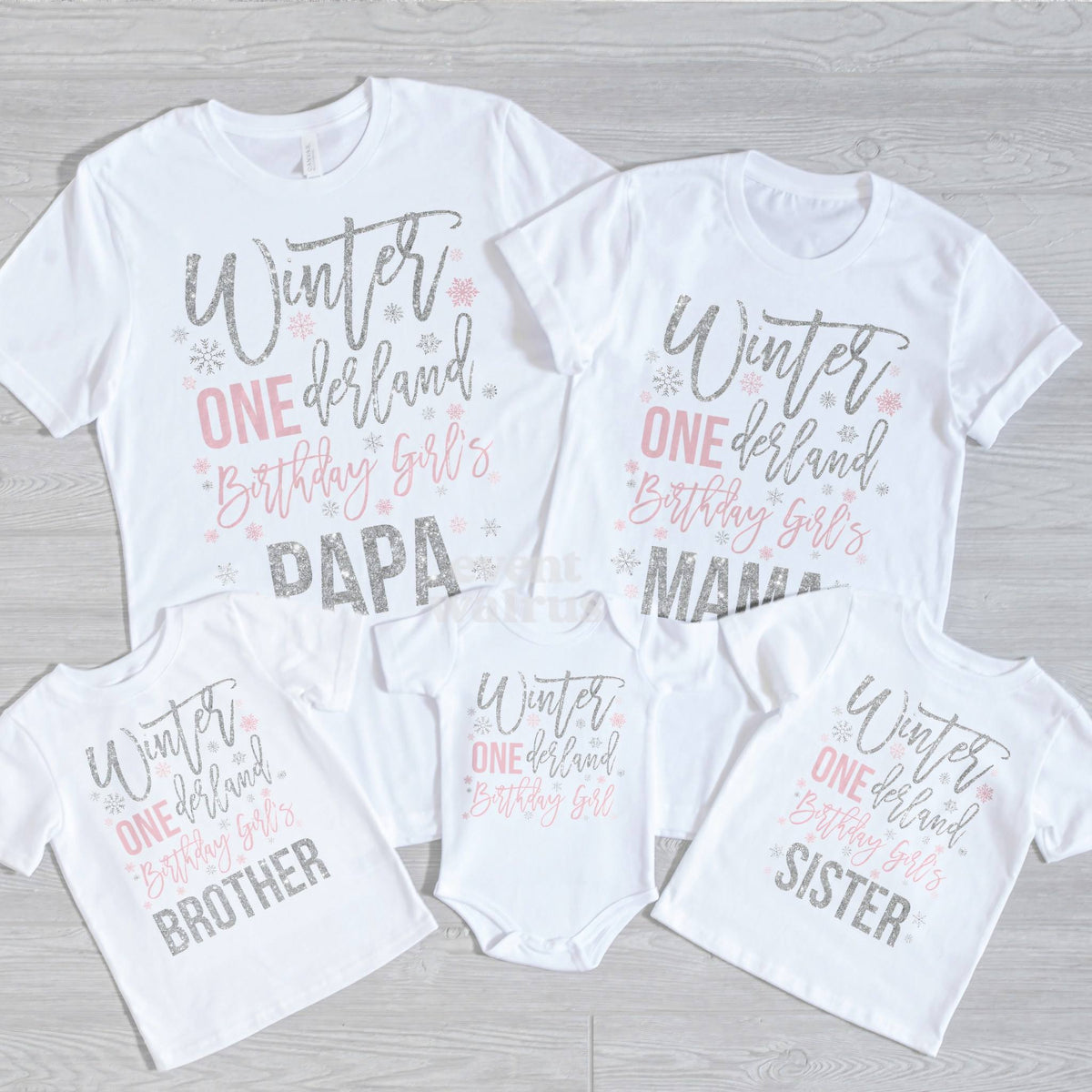 Papa, Mama, Brother, Sister and baby Winter ONEderland shirts laid out on gray wood.