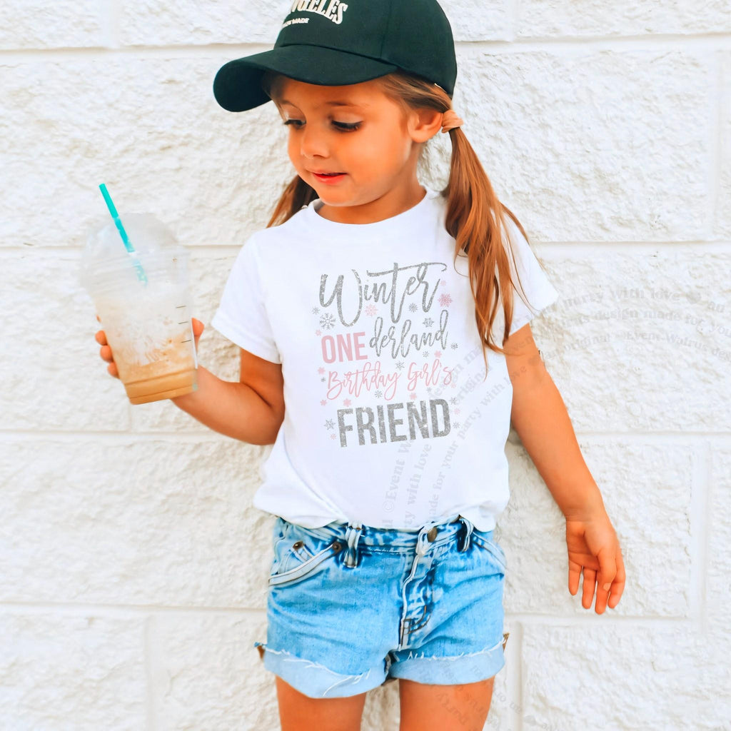 Girl in a ball cap holding a drink in a white Winter ONEderland Friend shirt.