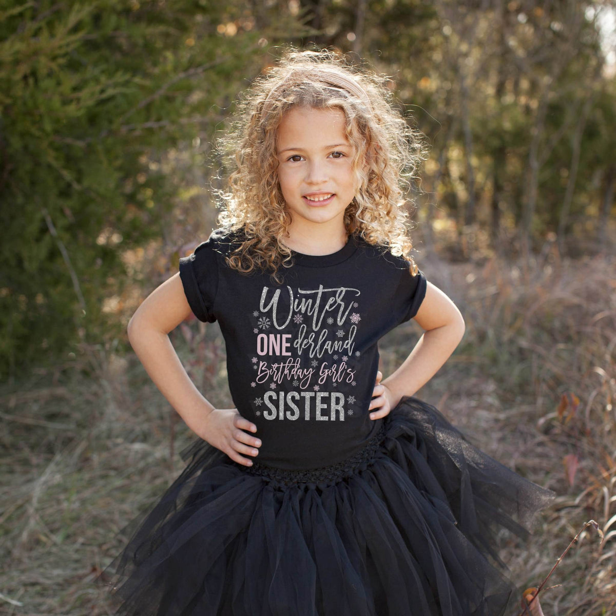 Girl in a black tutu and a black Winter ONEderland Sister shirt in a field.