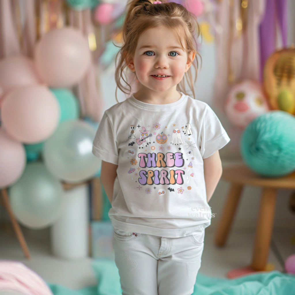 Smiling toddler girl at a pastel party in a white Three Spirit birthday tee.