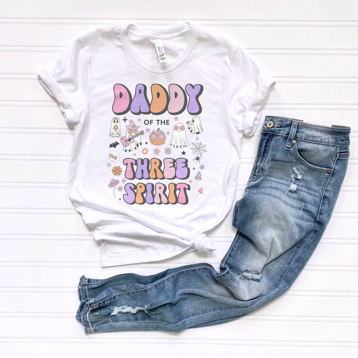White Daddy of the Three Spirit tee laid flat beside jeans.