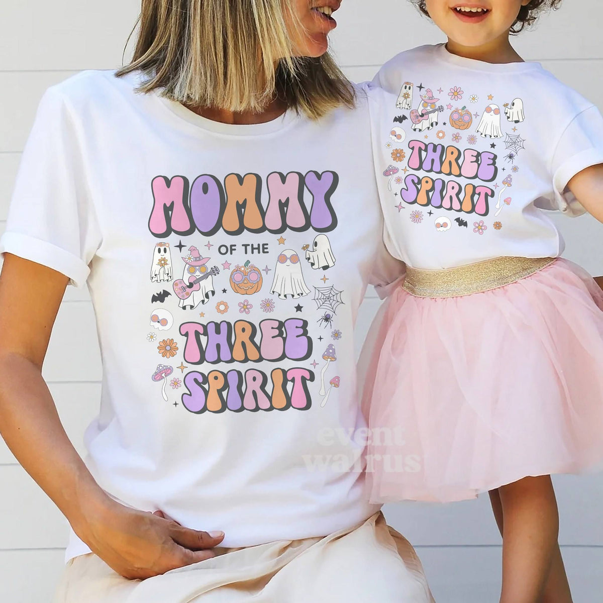 Mom holding hands with her little girl in a tutu, both in white Three Spirit shirts.