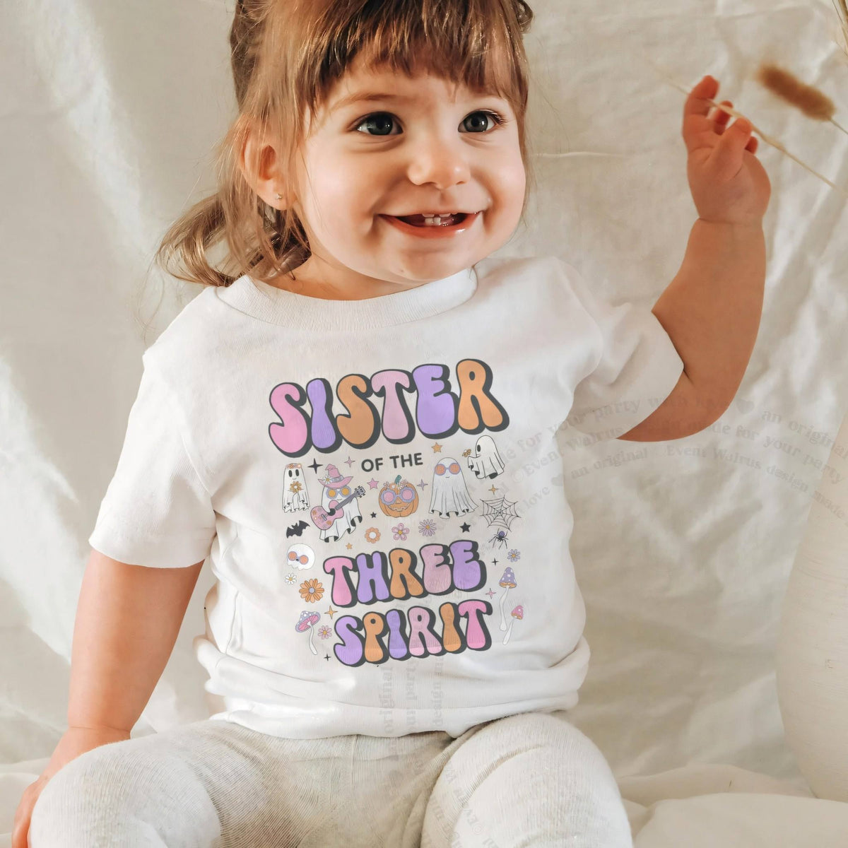 Laughing baby girl in a white Sister of the Three Spirit baby tee.