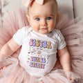 Baby girl with a pink bow on tulle in a white Sister of the Three Spirit bodysuit.