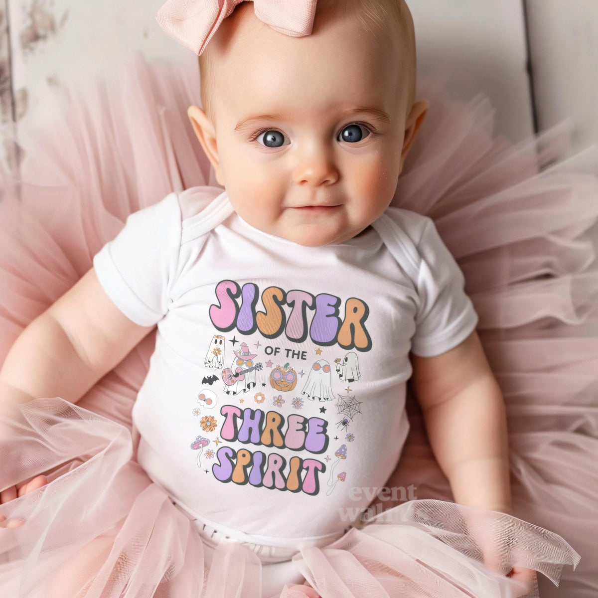 Baby girl with a pink bow on tulle in a white Sister of the Three Spirit bodysuit.