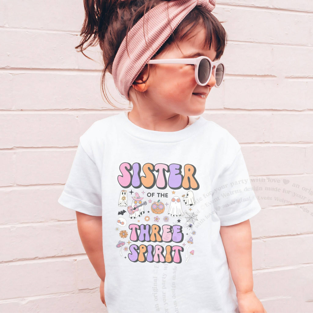 Girl in sunglasses and a pink headband wearing a white Sister of the Three Spirit shirt.