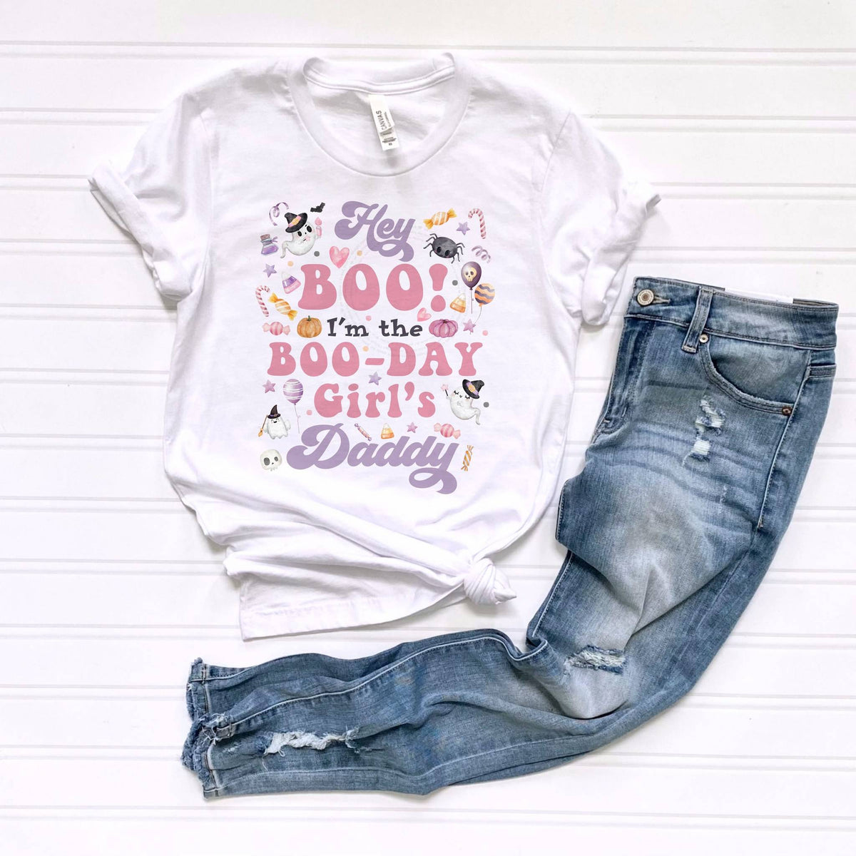 White Hey Boo Boo-Day Girl's Daddy tee laid flat beside jeans.