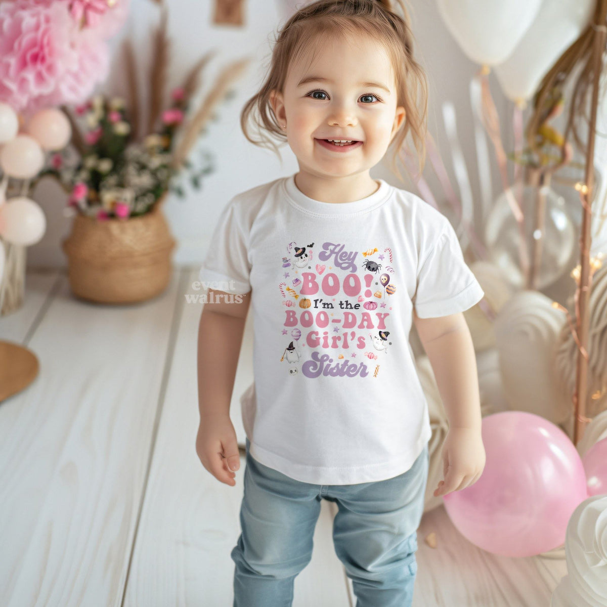 Toddler girl at a pink party in a white Hey Boo Boo-Day Girl's Sister tee.