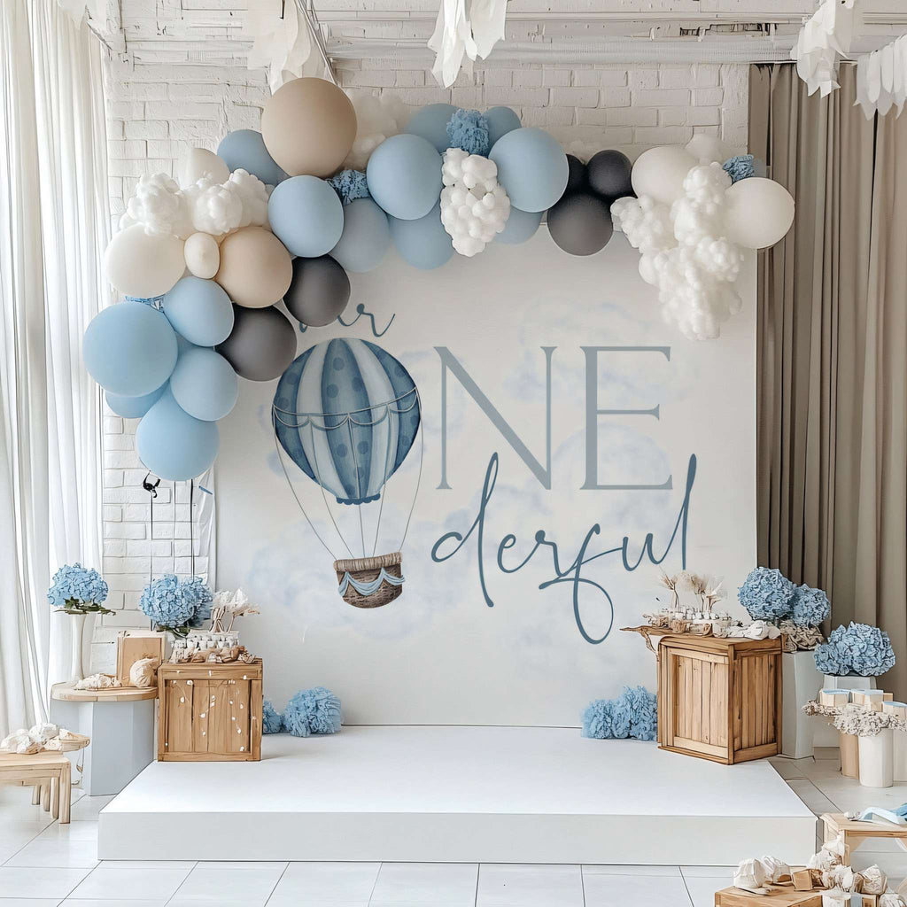Hot air balloon Mr Onederful backdrop with a blue, white and gray balloon garland and wooden crates.