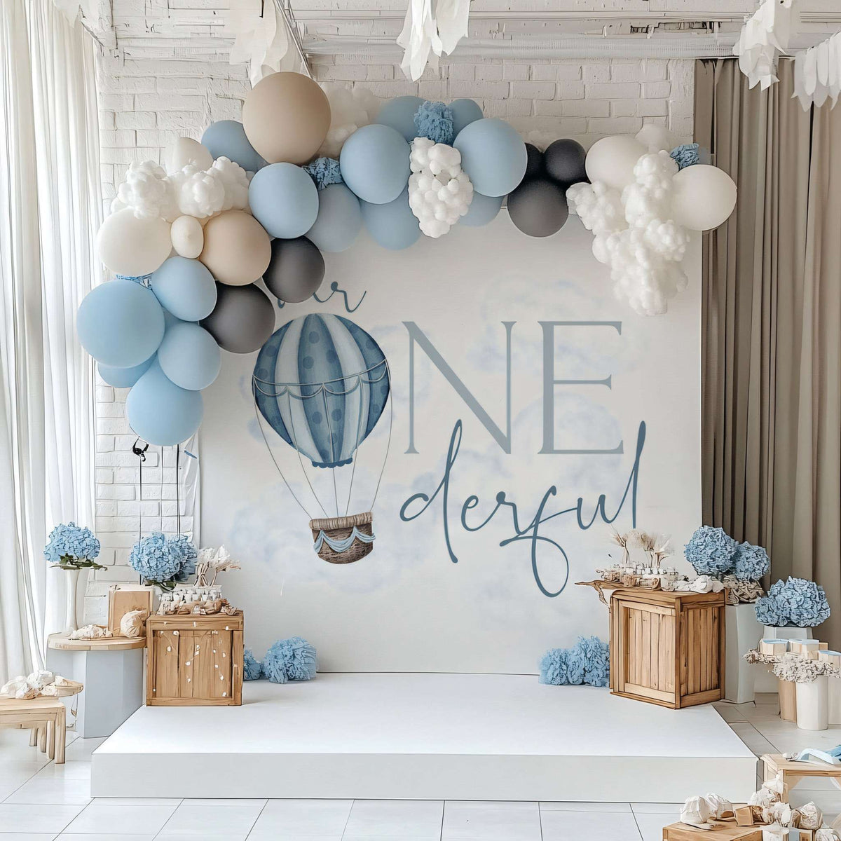Hot air balloon Mr Onederful backdrop with a blue, white and gray balloon garland and wooden crates.