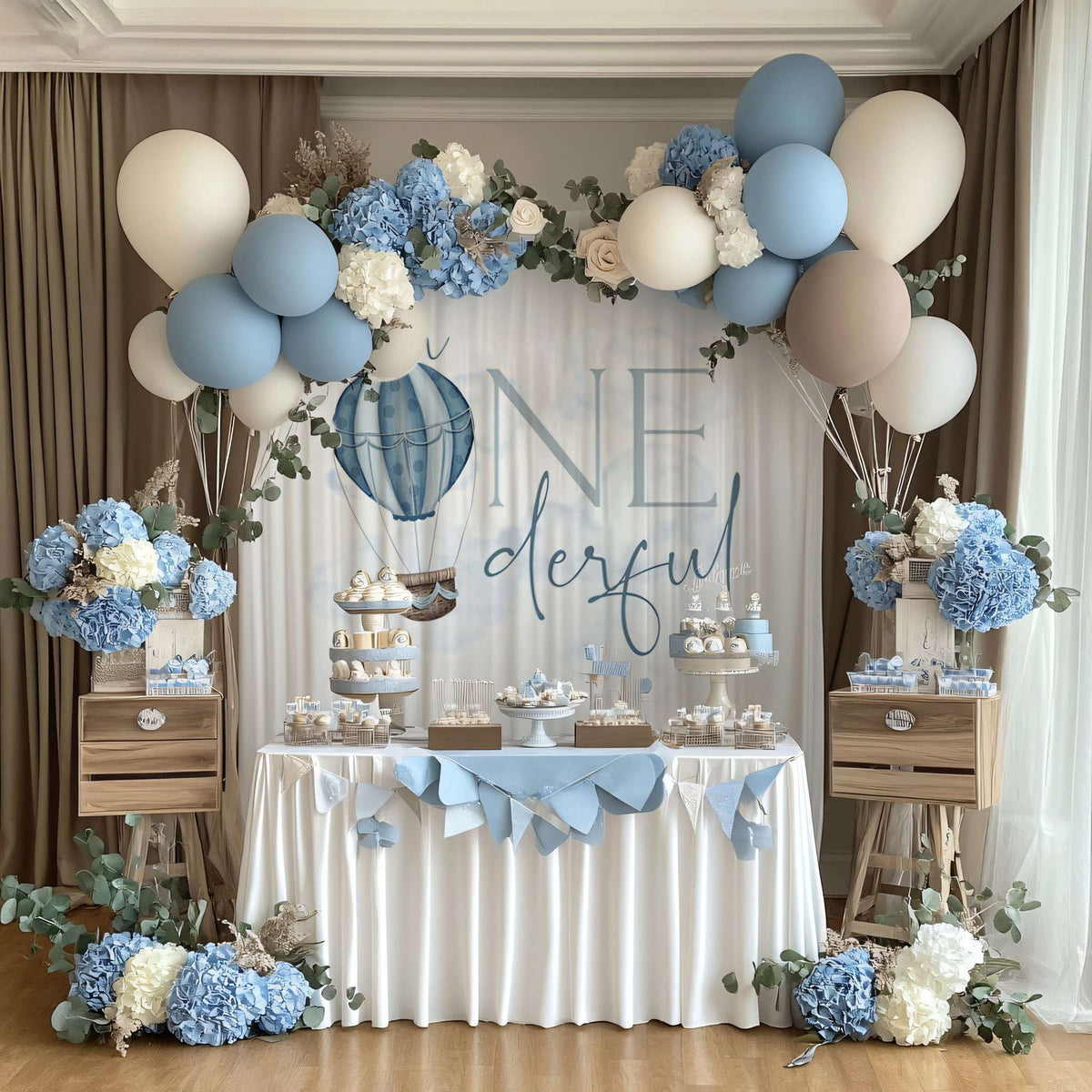 Mr Onederful hot air balloon backdrop framed by blue hydrangeas and a balloon garland over a cake table.