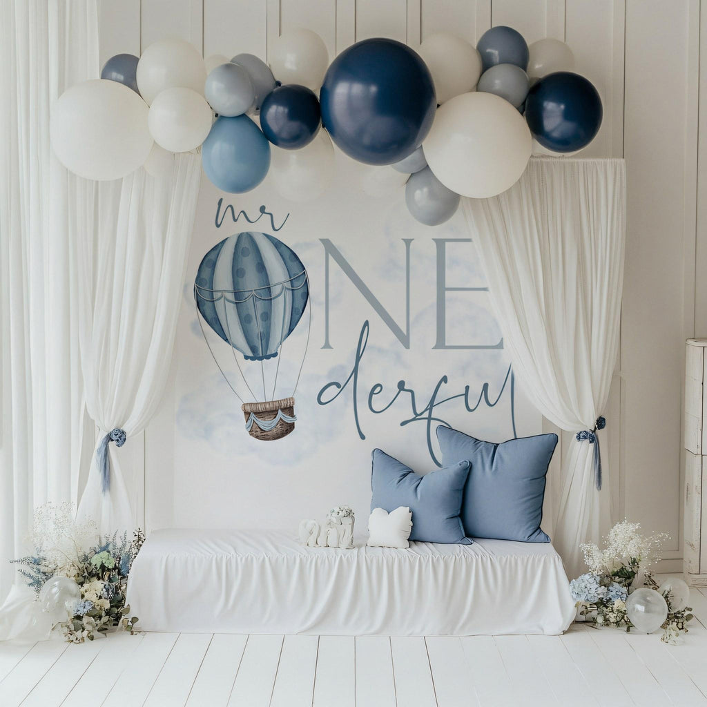 Mr Onederful backdrop behind a white bench with blue pillows for a cake smash.
