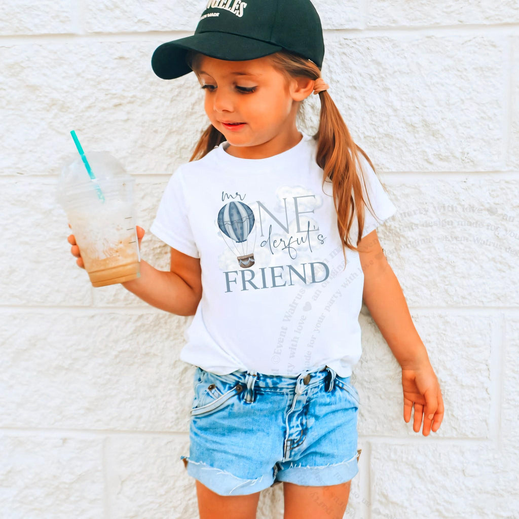 Girl in a ball cap holding a drink in a white Mr Onederful's Friend tee.