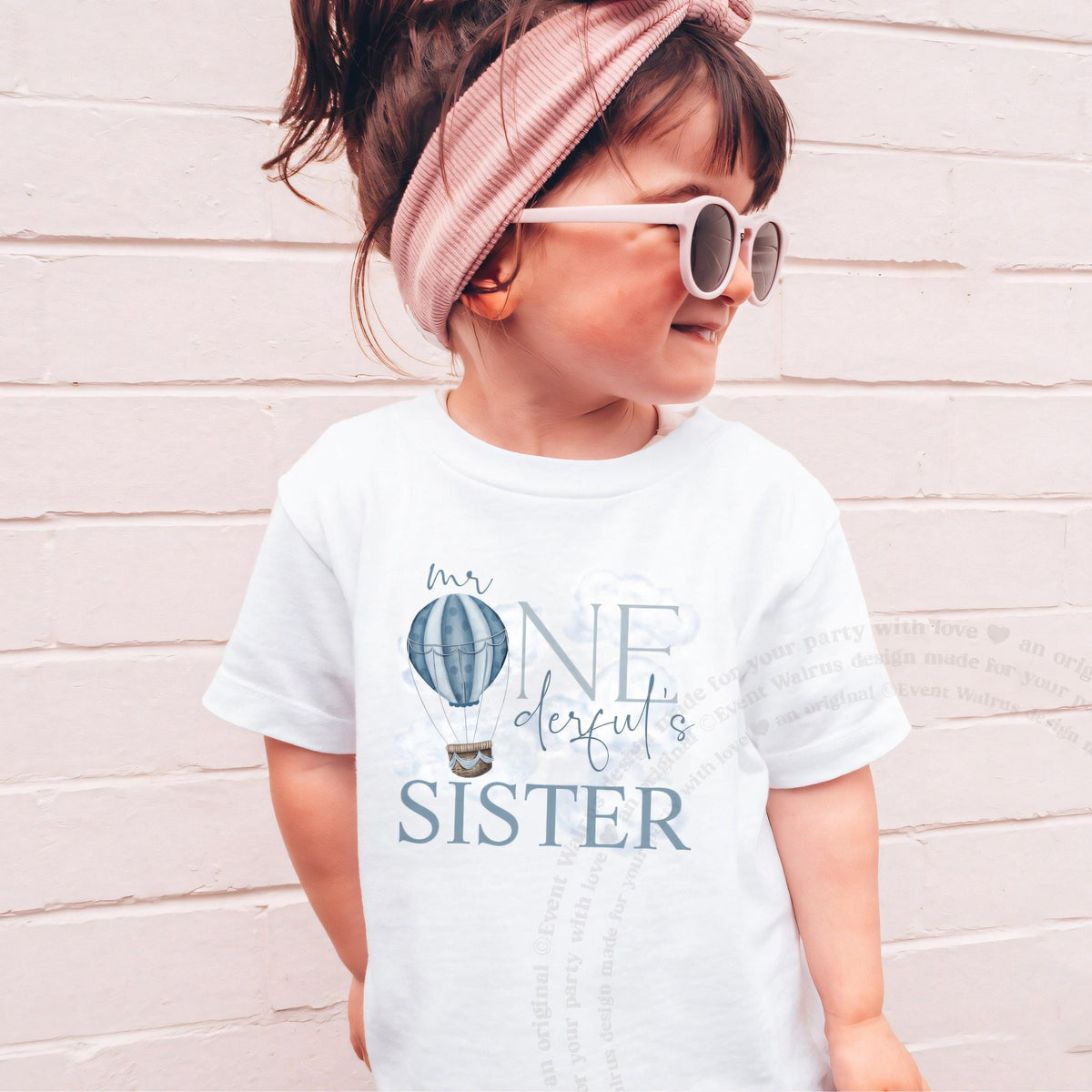 Girl in sunglasses and a pink headband wearing a white Mr Onederful's Sister tee.