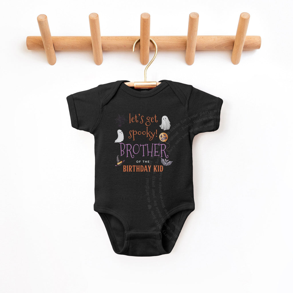 Black Brother of the Birthday Kid bodysuit hanging on a wooden peg rack.
