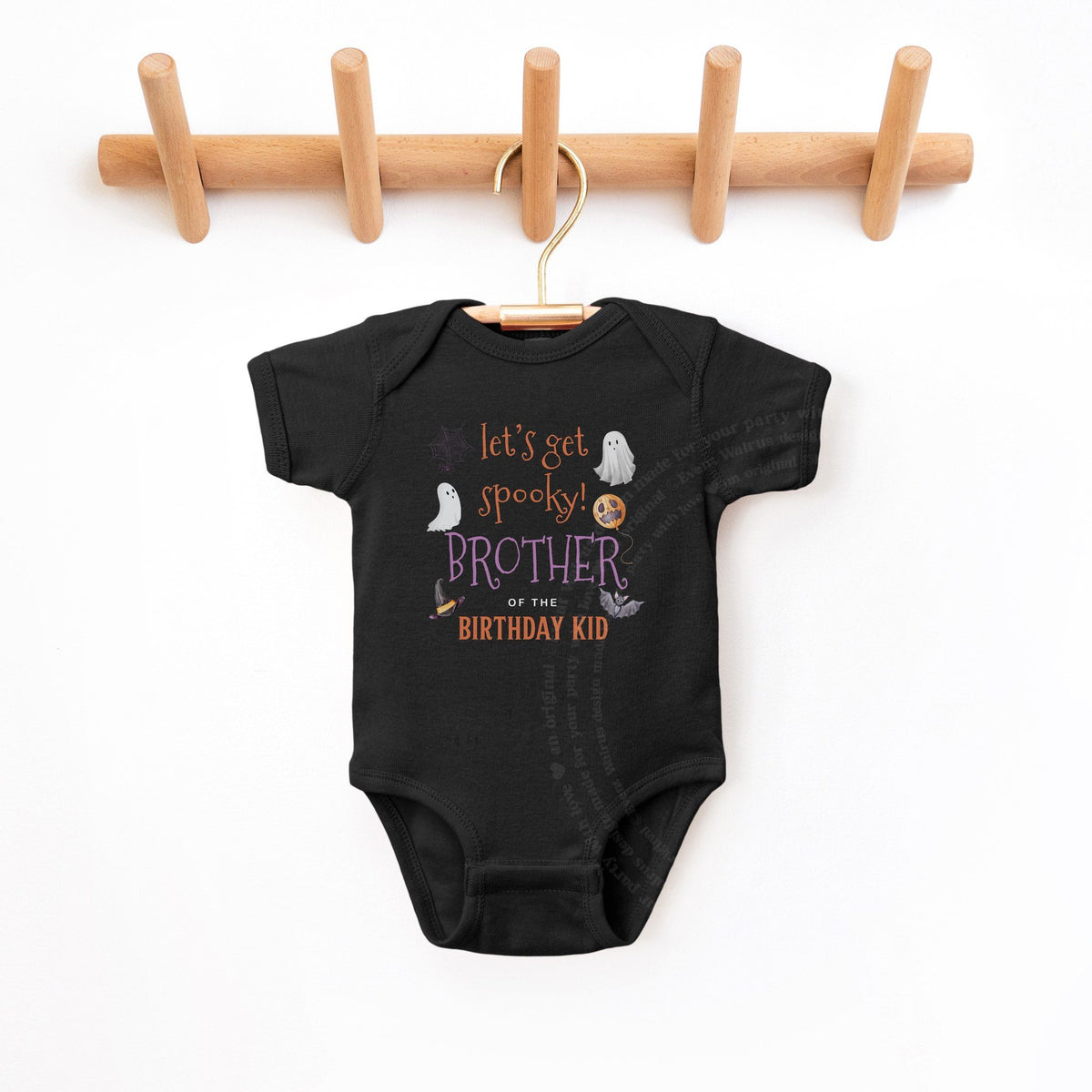 Black Brother of the Birthday Kid bodysuit hanging on a wooden peg rack.