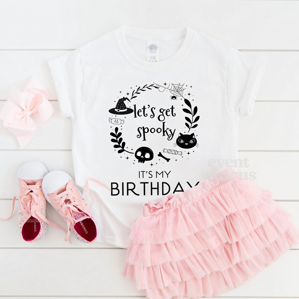White Let's Get Spooky It's My Birthday toddler tee laid flat with a pink tutu and sneakers.