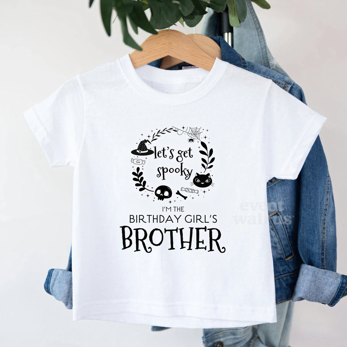 White Let's Get Spooky Brother toddler tee on a hanger over a denim jacket.