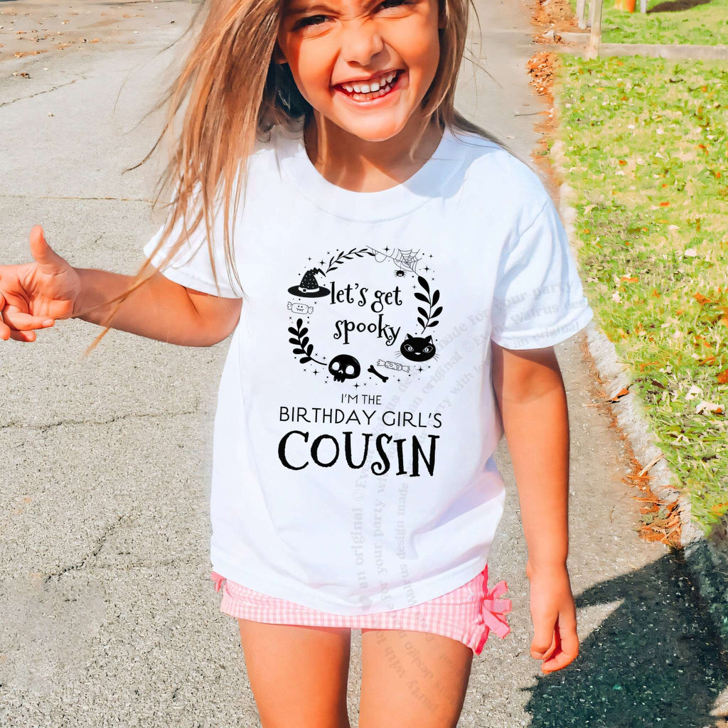 Laughing girl outdoors in a white Let's Get Spooky Cousin kids tee.
